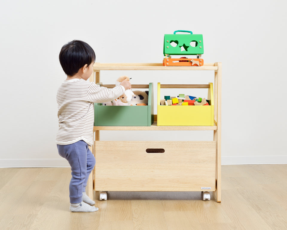 A child independently tidying toys into the Yamatoya Norsta3Kids Toy Rack, demonstrating the child-height accessible design.